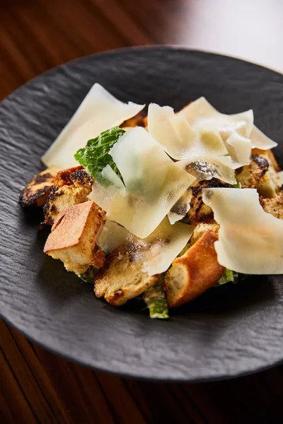 Gustosa insalata Caesar con fette di parmigiano servita sul piatto sul tavolo di legno — Foto stock