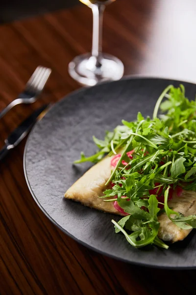 Foyer sélectif de délicieux steak de poisson restaurant avec de la chaux et de la roquette sur une table en bois près de couverts — Photo de stock