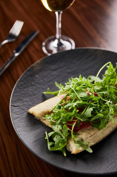 Selettiva messa a fuoco di gustosa bistecca di pesce ristorante con lime e rucola sul tavolo di legno vicino posate e vino — Foto stock