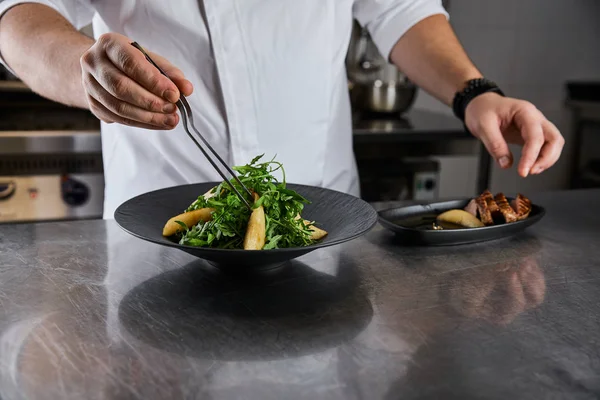 Vue partielle du plat de cuisine du chef avec roquette, viande et pomme de terre à la cuisine dans le restaurant — Photo de stock
