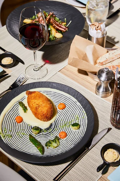 Pollo kiev con puré de papa servido en la mesa con bebidas en el restaurante - foto de stock