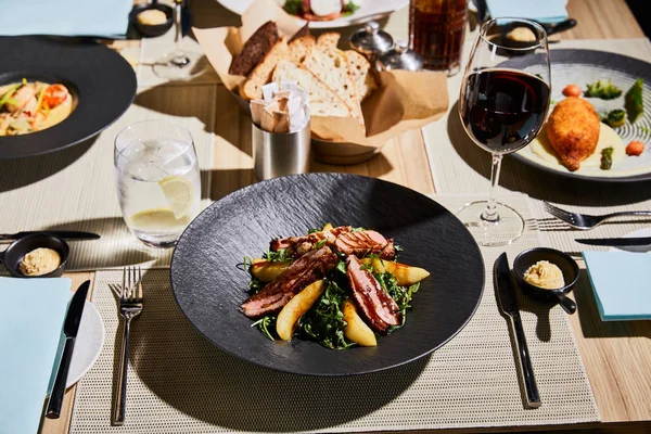 Delicious warm salad with meat, arugula, potato served on table in restaurant — Stock Photo