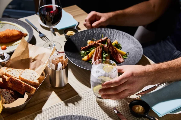 Vue recadrée de l'homme mangeant une délicieuse salade chaude au restaurant — Photo de stock