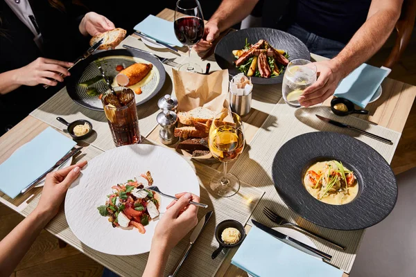 Vue recadrée des gens qui mangent de délicieux aliments pendant le dîner au restaurant — Photo de stock