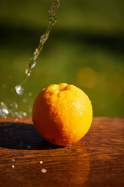 Foco seletivo de laranja inteira e molhada na superfície de madeira — Fotografia de Stock