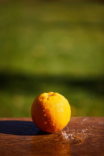 Selective focus of whole and wet orange on wooden surface — Stock Photo