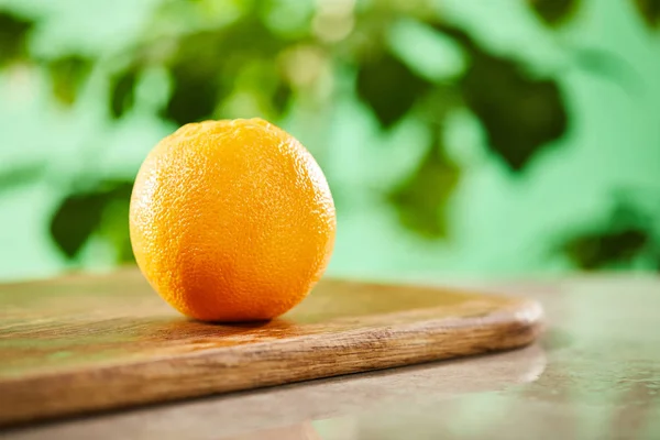 Selective focus of whole orange on wooden cutting board — Stock Photo