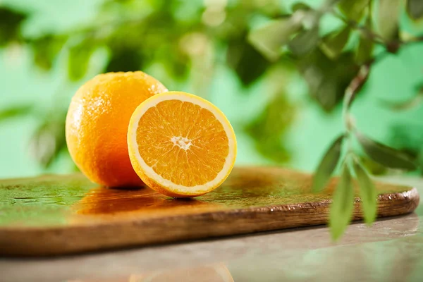 Selective focus of cut and whole oranges on wooden cutting board — Stock Photo