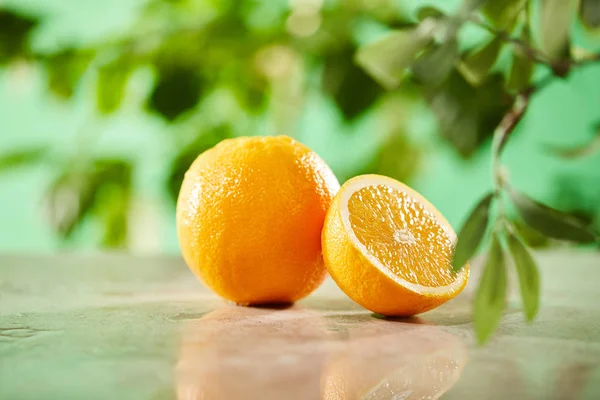 Mise au point sélective des oranges coupées et entières sur la surface du marbre — Photo de stock