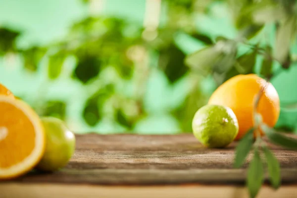 Mise au point sélective de la coupe, des oranges entières et des chaux sur la surface en bois — Photo de stock