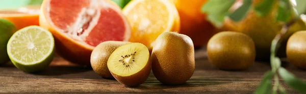 Selective focus of cut and whole kiwi on wooden surface — Stock Photo