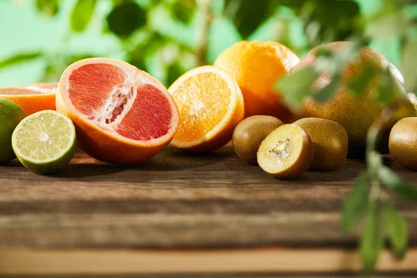 Selective focus of kiwi, oranges, lime, grapefruit and mango on wooden table — Stock Photo