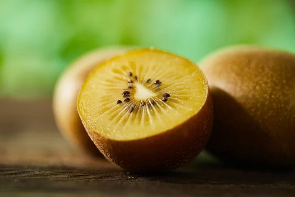 Close up view of cut and whole kiwi on wooden surface — Stock Photo