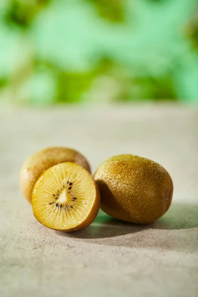 Selective focus of cut and whole kiwi on marble surface — Stock Photo