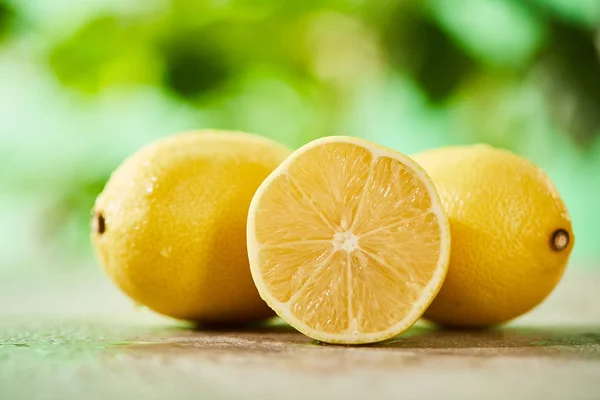 Selective focus of whole and cut lemons with drops on marble surface — Stock Photo