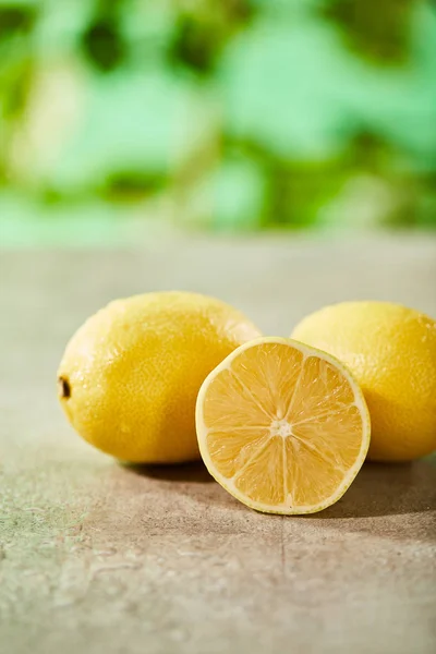 Selektiver Fokus von ganzen und geschnittenen Zitronen mit Tropfen auf Marmoroberfläche — Stockfoto