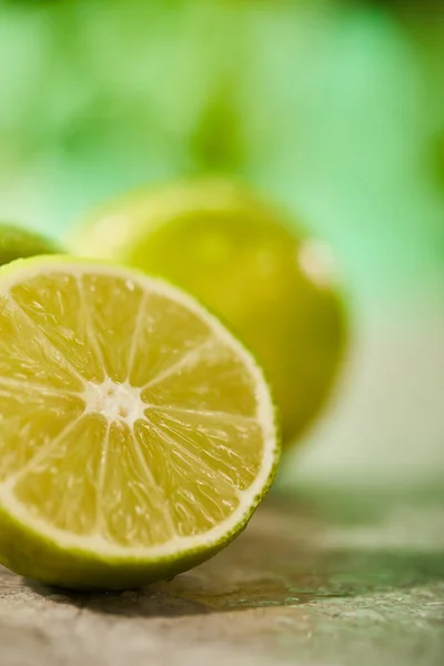 Close up view of fresh and cut lime on marble surface — Stock Photo