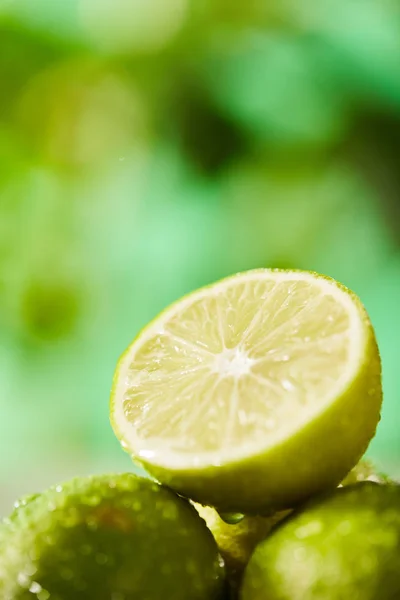 Nahsicht auf ganze und geschnittene Limetten mit Tropfen — Stockfoto