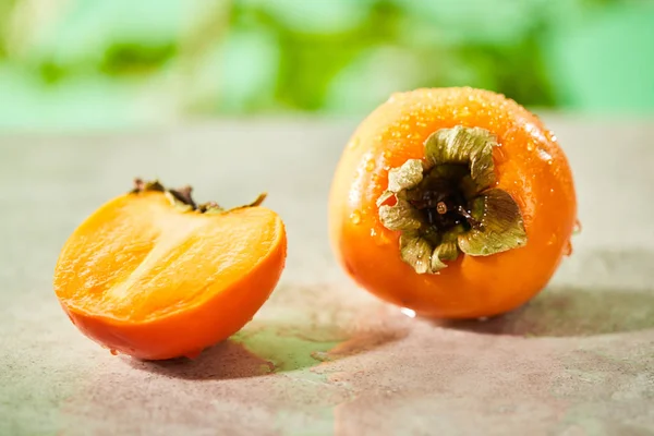 Selective focus of whole and cut persimmons on marble surface — Stock Photo
