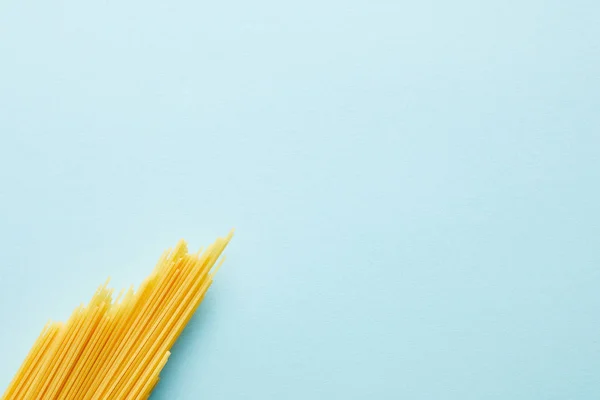 Vue du dessus des spaghettis crus sur fond bleu avec espace de copie — Photo de stock