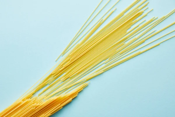 Top view of raw spaghetti on blue background with copy space — Stock Photo