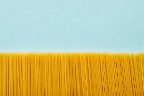 Vista dall'alto di spaghetti crudi su sfondo blu con spazio di copia — Foto stock