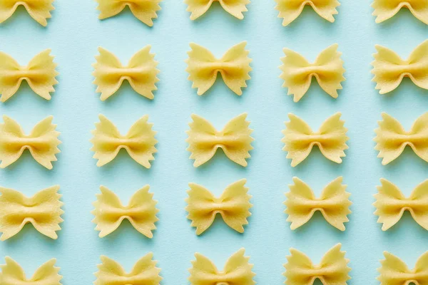 Flat lay with raw Farfalle on blue background — Stock Photo