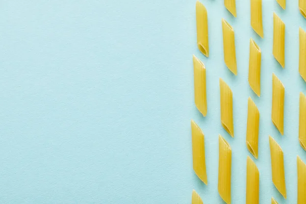 Flache Lage mit rohem Penne auf blauem Hintergrund mit Kopierraum — Stockfoto