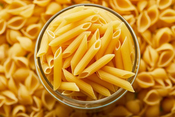 Top view of raw penne in jar and around — Stock Photo