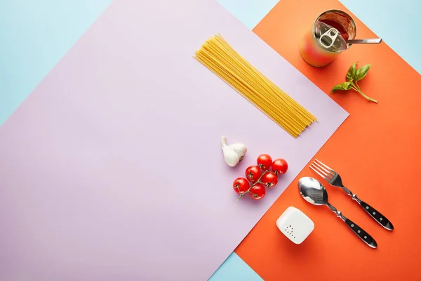 Flat lay com delicioso espaguete com ingredientes de molho de tomate em fundo vermelho, azul e violeta — Fotografia de Stock