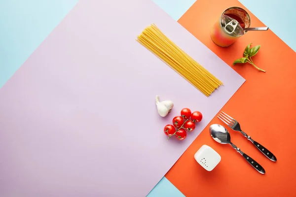Flat lay with delicious spaghetti with tomato sauce ingredients on red, blue and violet background — Stock Photo