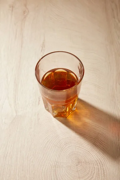 Glass of fresh beer on wooden beige surface with shadow — Stock Photo