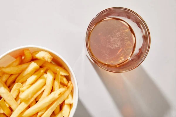 Top view of beer in glass near delicious french fries in bucket on white background — Stock Photo