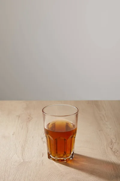 Glass of fresh beer on wooden beige surface on grey background — Stock Photo