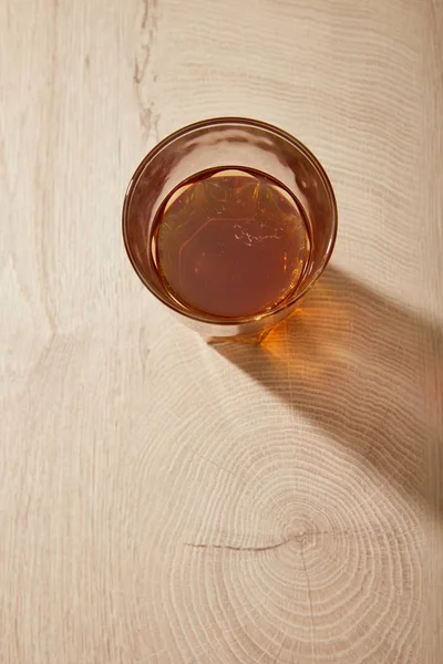 Vue du dessus du verre de bière fraîche sur la surface beige en bois avec ombre — Photo de stock