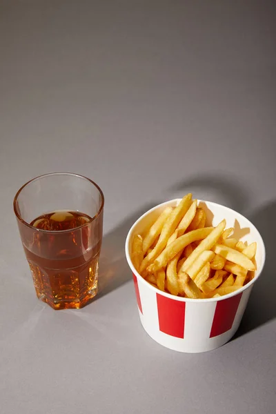 Beer in glass near delicious french fries in bucket on grey background — Stock Photo