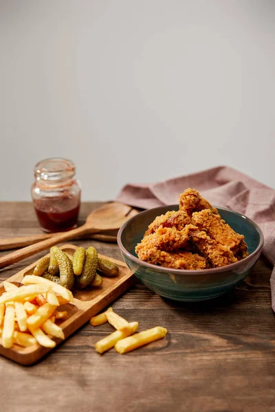 Délicieuses pépites de poulet, frites et cornichons sur table en bois isolé sur gris — Photo de stock