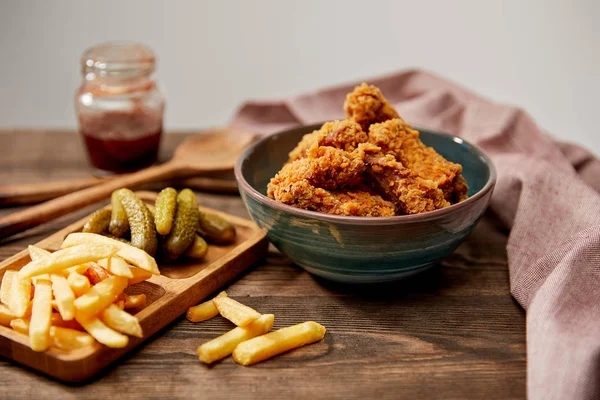 Foco seletivo de deliciosas pepitas de frango, batatas fritas e pepinos em mesa de madeira isolada em cinza — Fotografia de Stock