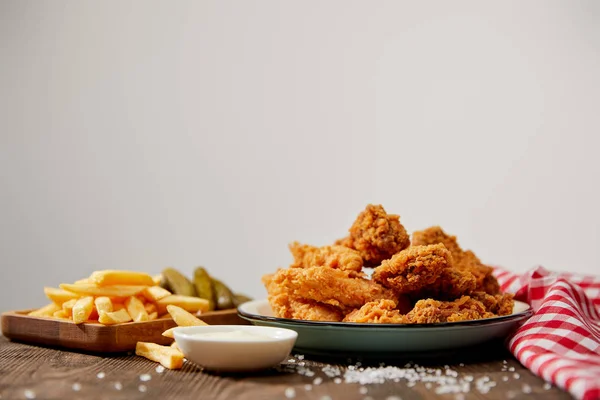 Deliciosas pepitas de pollo, ketchup, papas fritas y pepinillos cerca de vasos de cerveza sobre mesa de madera turquesa aislada en gris - foto de stock