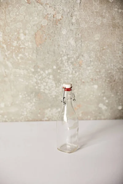 Empty glass bottle near stone grey wall — Stock Photo