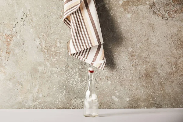 Порожня скляна пляшка біля смугастої серветки на кам'яній стіні — стокове фото