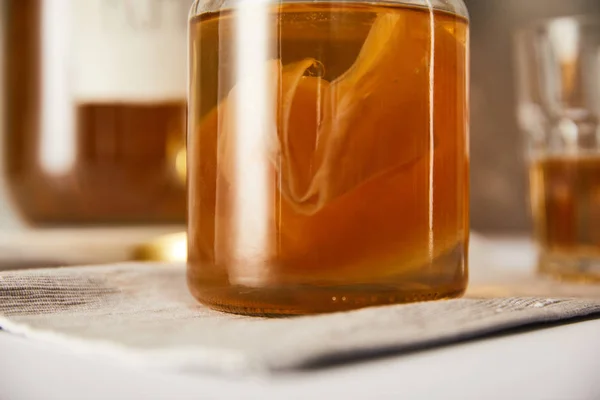 Close up view of jar with kombucha on grey napkin — Stock Photo