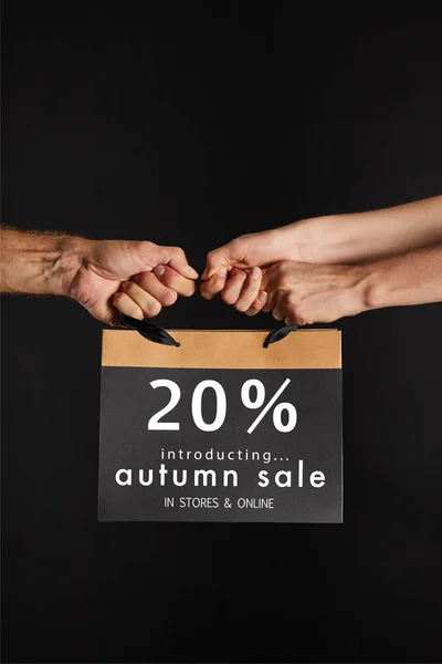 Partial view of woman and man holding paper shopping bag with 20 percent autumn sale illustration isolated on black, black Friday concept — Stock Photo