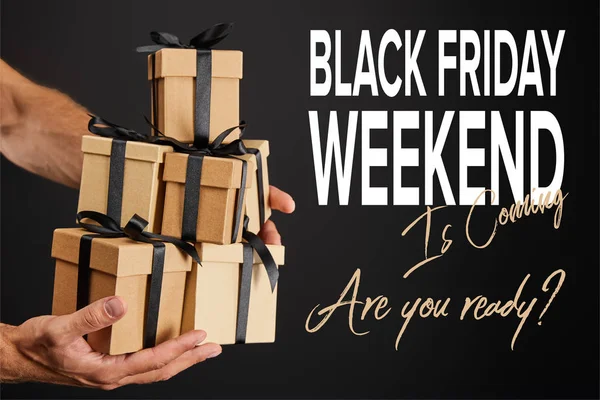 Cropped view of man holding cardboard gift boxes with ribbons isolated on black with black Friday weekend illustration — Stock Photo