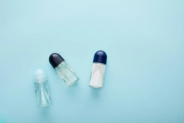 Draufsicht der Rolle auf Deodorant-Flaschen auf blauem Hintergrund — Stockfoto