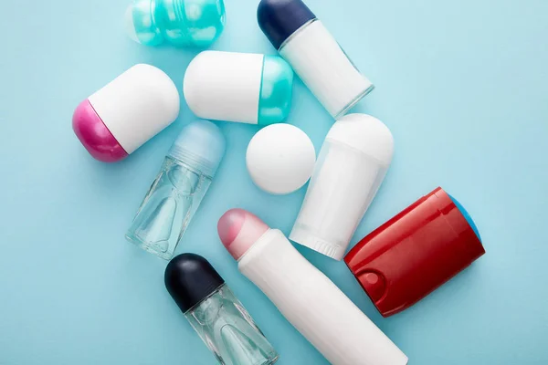 Top view of roll on and spray bottles of deodorant on blue background — Stock Photo