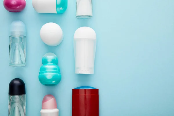 Flat lay with roll on and spray bottles of deodorant on blue background — Stock Photo