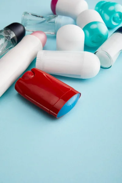 Arrotolare e spruzzare bottiglie di deodorante su sfondo blu — Foto stock