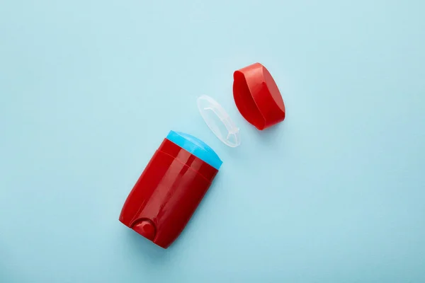 Vue du dessus du rouleau rouge sur bouteille de déodorant sur fond bleu — Photo de stock