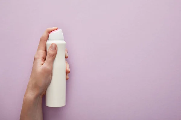 Vista cortada da mulher segurando desodorizante spray no fundo violeta com rosas brancas — Fotografia de Stock